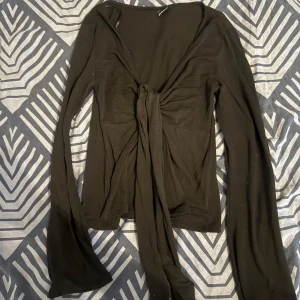 Svart långärmad topp från Gina Tricot - Snygg svart långärmad topp från Gina Tricot med knytning framtill. Perfekt för en stilren look. Passar bra till både jeans och kjol.