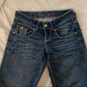 Blå jeans från Hilfiger Denim - Snygga blå jeans från Hilfiger Denim med klassisk femficksdesign och knappgylf. Jeansen är bootcut/straight💕