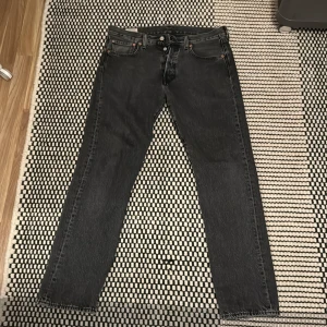Svarta jeansbyxor från Levi's 501 - Snygga svarta jeansbyxor från Levi's med klassisk femficksdesign och knappgylf. Köpt på Levi’s egna hemsida för något år sedan. Använt sparsamt och är i ett bra skick! Skick 9/10! 