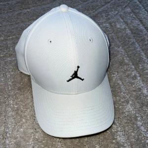 Air jordan Keps Vit - Snygg vit keps från Jordan med den ikoniska Jumpman-loggan framtill. Kepsen har en klassisk design med böjd skärm och ventilationshål för extra komfort. Perfekt för en sportig look.