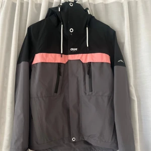 Skidjacka från Dope - Snygg grå och svart jacka från Dope med rosa detaljer. Jackan har en justerbar huva och dragkedjor på bröstfickorna. Varan är i mycket bra skick och har inga synliga defekter! Pris kan diskuteras🤗