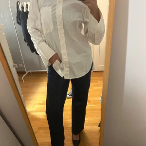 Vit skjorta med fickor - Säljer en klassisk vit skjorta med långa ärmar och två bröstfickor. Skjortan har en oversized passform och knäppning framtill. Perfekt för en stilren look. Nyskick! 