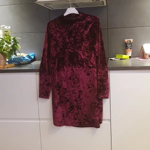 Vinröd sammetsklänning från Gina Tricot - Snygg vinröd klänning i sammet från Gina Tricot. Klänningen har en elegant, mörk ton och långa ärmar, perfekt för höst och vinter. Den har en klassisk passform som ger en stilren look.