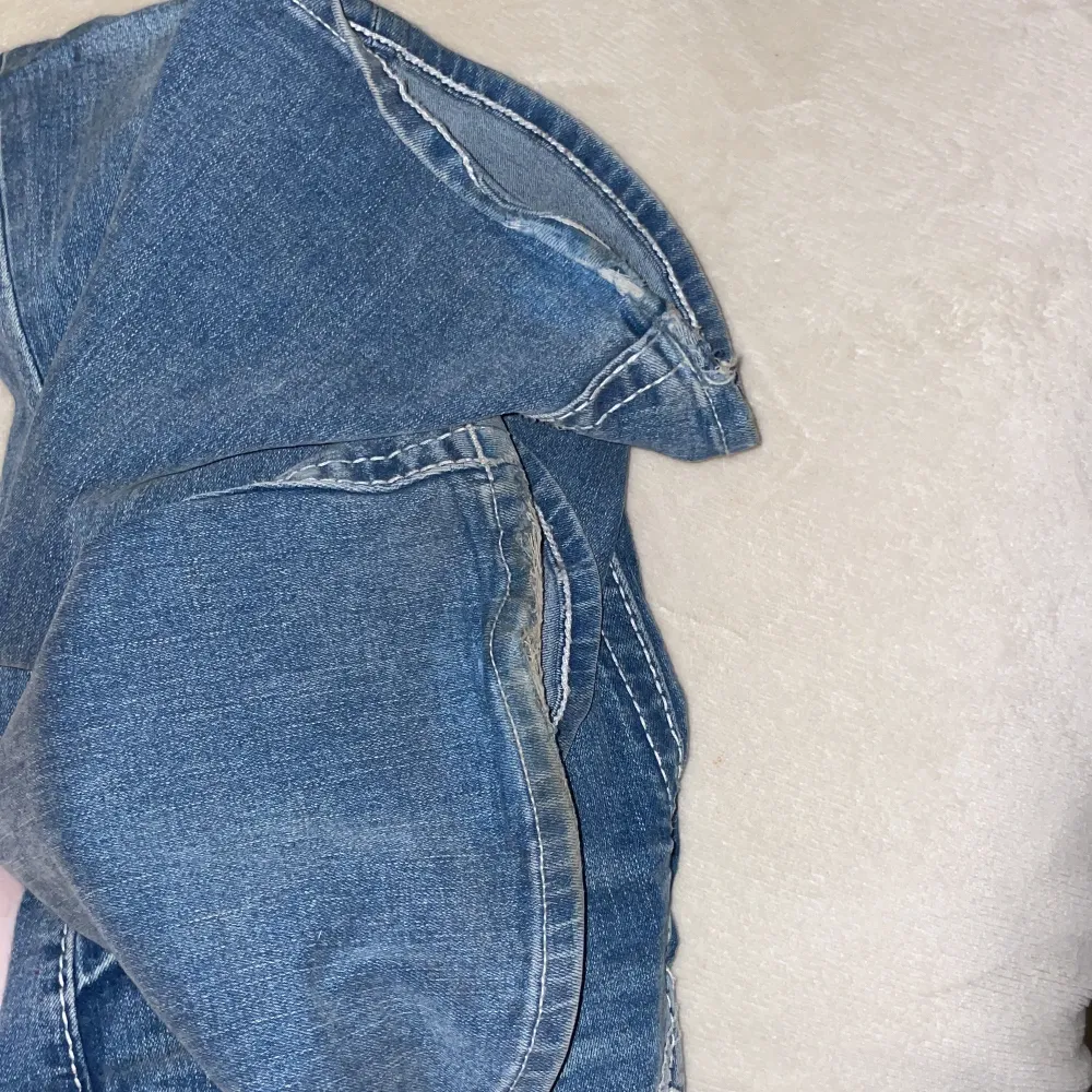 Säljer mina superfina true religion jeans då jag har köpt ett par nya. De är köpta helt nya i somras för 1600 kr och i fint skick förutom slitningar nere vid fötterna, jag är 165 cm och dom är lagom/lite för långa för mig och sitter jättebra.. Jeans & Byxor.