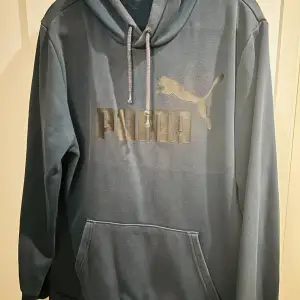 Säljer en snygg mörkblå hoodie från Puma i storlek M. Den har en klassisk design med en stor Puma-logga på framsidan och en bekväm känguruficka. Perfekt för både vardag och chill. Huvan är justerbar med dragsko och materialet känns mjukt och skönt. Passar perfekt till höst och vår!