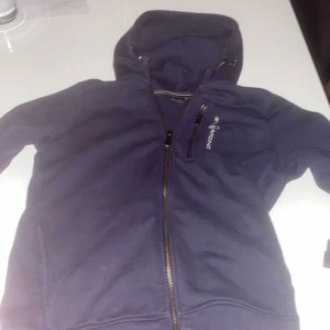 Sailracing zip hood blå  - Jag säljer denna eftersom jag har tyvärr växt ur den.  Den har en fläck som man kan se på andra bilden men annars är den helt okej