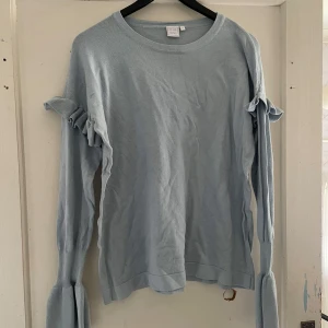 Ljusblå tröja med volangdetaljer från Club XPRS - Säljer en superfin ljusblå tröja från Club XPRS. Den har långa ärmar med volangdetaljer som ger en söt touch. Perfekt för både vardag och fest! 💙