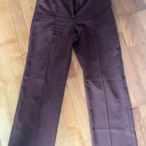 Bruna höga kostymbyxor  - Säljer mina bruna högmidjade kostymbyxor från madlady. Fortfarande bra skick men har använt rätt mycket. Säljer endast för att de är för små