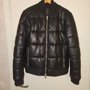 AllSaints läderjacka  - Stilren läderjacka i nyskick!. Perfekt kombination av värme och exklusiv design, med robusta dragkedjor och ribbade muddar. Ett mångsidigt plagg för både kalla dagar och en modern vardagslook.