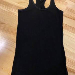 Svart tank top/linne - Svart linne med brottarrygg i en lite längre modell från Cubus. Strl S. Något urtvättad. 