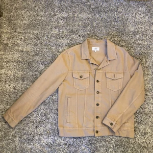 Beige jeansovershirt från Celio - Säljer en stilren beige jeans overshirt från Celio. Den har en klassisk design med knappar framtill och två bröstfickor med lock. Den är i storlek XL på papper men skulle säga att den mer lutar åt en L med boxy-aktig fit och en aningen lösare passform. Om du önskar ytterligare info eller specifika bilder så är det bara att skriva 🙏