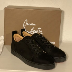 Svarta sneakers från Christian Louboutin - Snygga svarta sneakers från Christian Louboutin i mocka med den ikoniska röda sulan. Skorna har snörning och en stilren design som passar perfekt för en trendig look. Levereras med originalförpackning och dustbag. Finns inte din storlek? Vi kan fixa alla storlekar bara att höra av sig så löser vi de du vill ha! Vi kan även fixa alla skor, tröjor, jackor, västar osv till riktigt bra pris bara att skicka bild på vad du söker och storlek så ska vi göra de vi kan!/// Es Clothing se mindre