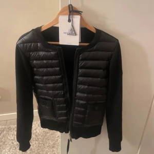 Svart jacka från Moncler - Snygg svart jacka från Moncler med quiltade detaljer och dragkedja framtill. Jackan har långa ärmar och två fickor med knappar. Perfekt för en stilren look. Äkta vilket man ser på bilderna! Kom priv för frågor elr fler bilder. LÄGSTA JAG GÅR ÄR 3000 (strlk 1 vilket motsvarar xs)
