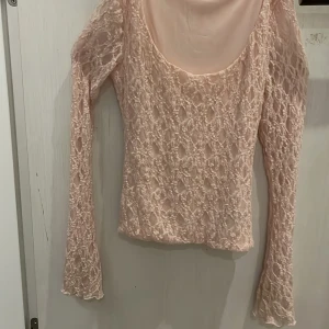Rosa spetsblus från Gina Tricot - Säljer en söt rosa spetsblus från Gina Tricot i storlek XS. Blusen har långa ärmar och ett vackert spetsmönster som ger en romantisk känsla. Perfekt för att piffa upp din garderob! 💖