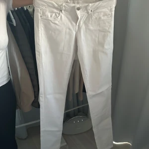 Vita skinny jeans från Guess - Snygga vita skinny jeans från Guess i modellen 'Jegging Ultra Skinny Low'. De har en låg midja och klassisk femficksdesign med en liten metallogo på bakfickan. Perfekta för en stilren look. Storlek midja 29