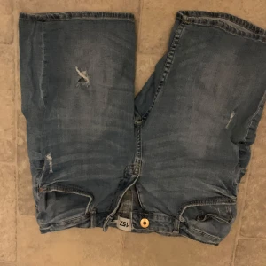 Blå jeansshorts från lager157  - Säljer ett par coola blå jeansshorts från lager157 med slitna detaljer. Perfekta för en avslappnad stil. De har en knapp och dragkedja framtill. Saknar storlek men är nog som 38 skulle jag säga