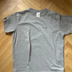 Grå t-shirt med broderad detalj - Säljer en enkel och stilren grå t-shirt från Nudie Den har en liten broderad detalj på bröstet och är kortärmad. 