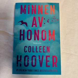 Minnen av honom - Nyskick!  Boken 'Minnen av honom' av Colleen Hoover är en gripande berättelse som har toppat New York Times bestsellerlista. Omslaget är turkost med rosa och vita detaljer, och visar silhuetter av fåglar mot en himmel. Perfekt för dig som älskar emotionella och fängslande romaner.