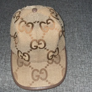 Beige keps med GG-mönster - Snygg beige keps med det ikoniska GG-mönstret i brunt. Kepsen har en klassisk design med böjd skärm och justerbar passform. Perfekt för en stilren look.