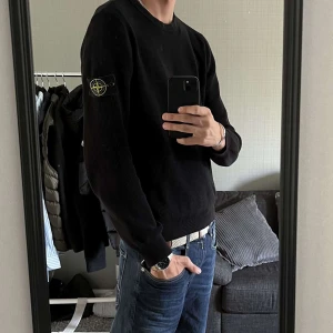 Svart tröja från Stone Island - Säljer en stilren svart tröja från Stone Island med deras ikoniska märke på ärmen. Tröjan är ribbad och har långa ärmar, perfekt för en casual look. Passar bra till jeans eller chinos.