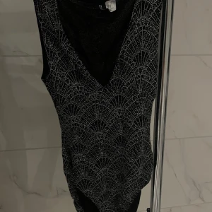 Glittrig Body - Glittrig body med v-ringing från Nelly i storlek XS. Knappast använd så inga defekter. Säljs inte på hemsidan! Pris går att diskutera🤗