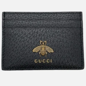 Svart kortfodral från Gucci - Snyggt svart kortfodral från Gucci i skinn med ett elegant guldfärgat bi och logotyp på framsidan. Perfekt för att hålla dina kort organiserade med stil. En lyxig accessoar för den modemedvetna.