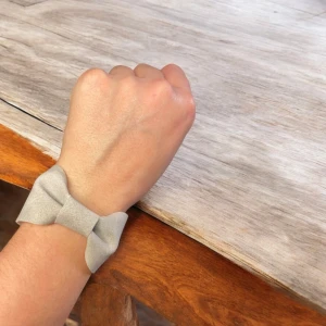 Beige armband med rosett - Elegant beige armband med en stilren rosett-design av konstläder. Armbandet har en enkel låsmekanism och är tillverkat i ett mjukt material som ger en bekväm passform. Perfekt för att ge en subtil touch av stil till din outfit.