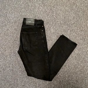 Svarta jeansbyxor - Snygga svarta jeansbyxor med klassisk design. De har en rak passform och är perfekta för en stilren look. Byxorna har fem fickor och knappgylf. Byxorna är från Jack and Jones. Är i passformen Loose och är i storleken 28/32