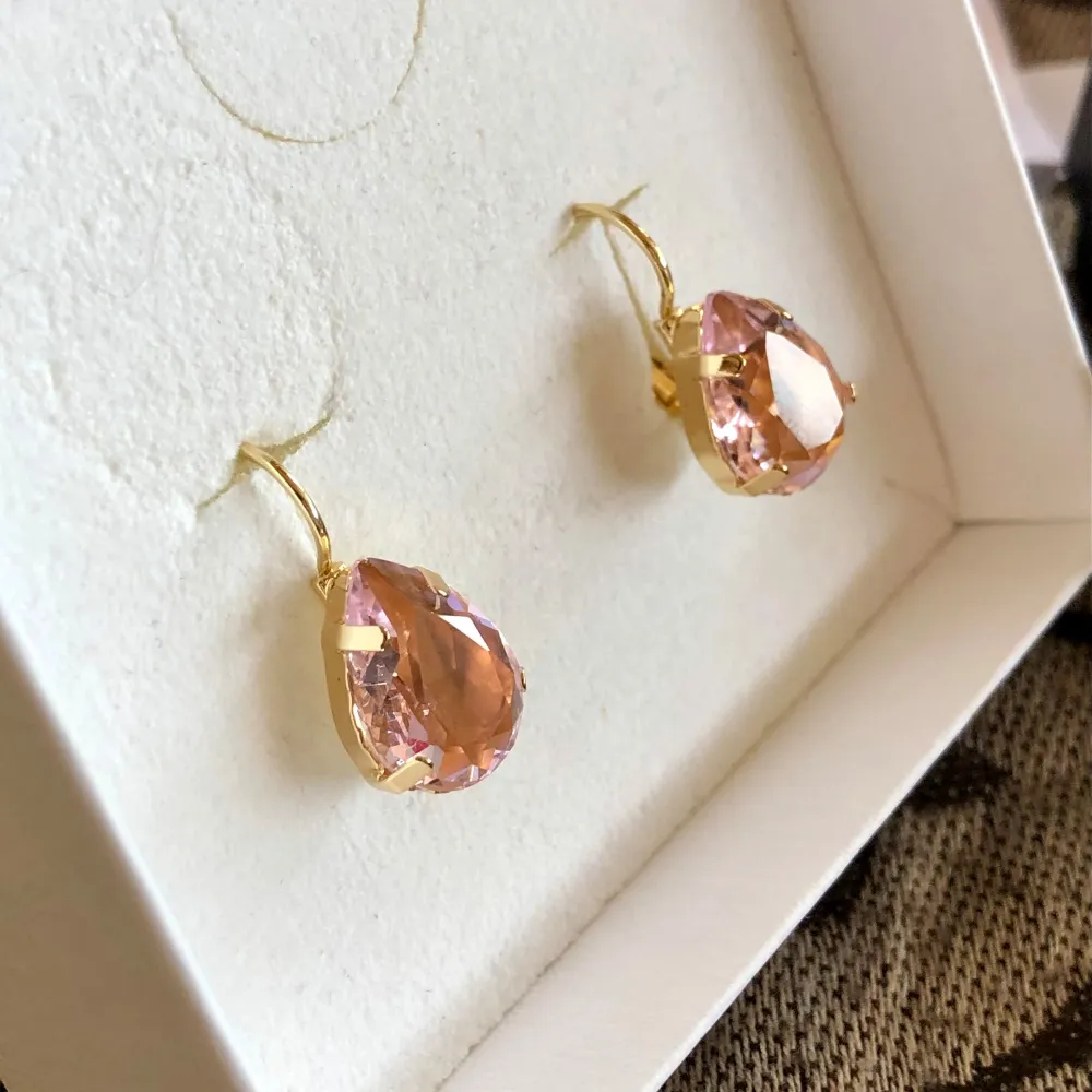 Fina örhängen i guld färgad metall med en ljusrosa diamant som är formad som en droppe I perfekt skick då jag använt dem bara någon enstaka gång. De ser ut som nya. Ask följer inte med men skickar i en smyckes påse . Asusteet.