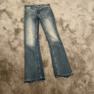 Blå bootcut jeans från Bershka - Snygga blå bootcut jeans från Bershka med slitna detaljer vid fållen. De har en klassisk femficksdesign och en knappgylf. Jag har sprättat upp de dör nere så de ska bli lite längre. Säljer då de är lite för korta för mig som är 175 cm.