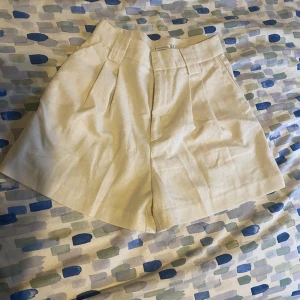 Beige shorts från Stradivarius - Snygga beige shorts från Stradivarius med hög midja och stilrena veck framtill. Perfekta för en somrig look. De har hällor för bälte och en klassisk design som funkar till många tillfällen.