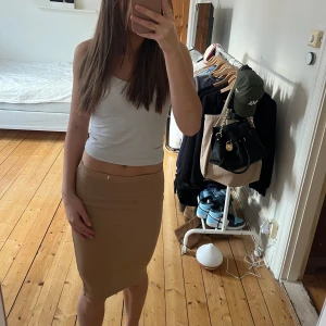 Beige glittrig kjol/klänning - Snygg beige glittrig kjol i en tight passform. Kjolen är kort och har en elastisk midja för extra komfort. Den funkar även som klänning. Storlek: XS/6