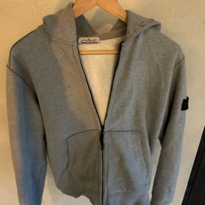 Grå hoodie från Stone Island - Säljer denna gråa zip tröja från Stone Island! Sjukt snygg och i väldigt bra skick. Storlek XS men passar även S! Skriv vid prisförslag eller funderingar