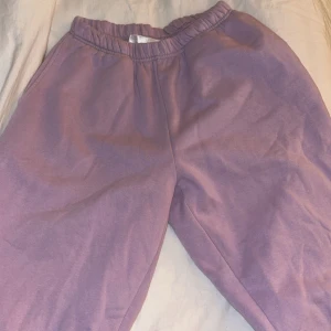 Lila mjukisbyxor - Säljer ett par bekväma lila mjukisbyxor med elastisk midja. Perfekta för en avslappnad dag hemma eller en promenad i parken. Byxorna har en mjuk och skön känsla.