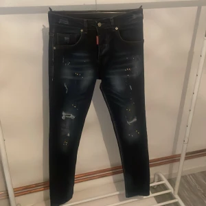 Svarta jeans från Dsquared2 - Snygga svarta jeans från Dsquared2 med coola slitningar och detaljer. De har en klassisk femficksdesign och en knappgylf. Perfekta för en trendig look.