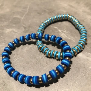 Blå och guld armband - Två stilrena armband i blått och guld. Det ena har en mix av blå och guldpärlor, medan det andra har blåa skivor med gulddetaljer. Perfekta för att ge en färgklick till din outfit! Båda för 100kr ett för 5kr