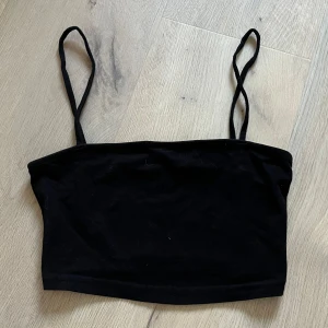 Svart kort topp från H&M - Snygg svart kort topp från H&M med smala axelband. Perfekt för en stilren look. Tillverkad i ett mjukt och bekvämt material. Kostade 30 kr när jag köpte de. Använt 1 gång. Den är som nytt skick. Super fin och otroligt skönt! 😍😍Perfekt för varma sommar dagar!