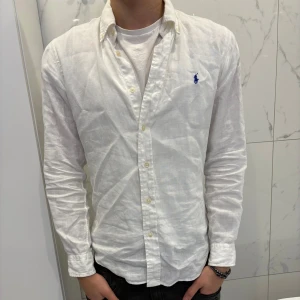 Vit skjorta från Ralph Lauren - Säljer en stilren vit skjorta från Ralph Lauren i slim fit. Perfekt nu till sommaren 🤩. Modellen är 181cm och 67kg. Skjortan är köpt på Plick. Den är i mycket bra skick och finns inga defekter då den är använd ett fåtal gånger 👍🏾. Pris kan diskuteras 😁