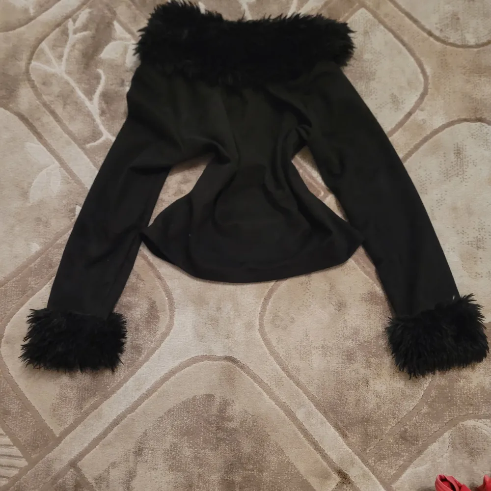 Snygg svart jacka med dragkedja och fuskpälsdetaljer vid krage och ärmslut. Tillverkad i polyester och elastan för en bekväm passform. Perfekt för att ge en extra touch till din outfit. Jag vet inte vilket märke, jag köpte den några år sedan men använde bara ett par gånger.. Takit.