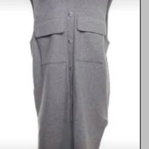 Grå ytterväst med knappar - Snygg grå väst med knappar framtill och två stora fickor. Perfekt för lager-på-lager-stil och ger en stilren look. Passar bra till både vardag och mer uppklädda tillfällen.
