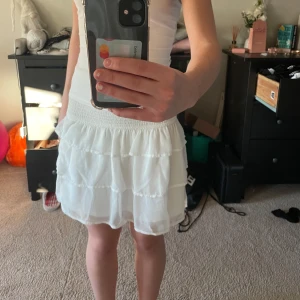 Vit volangkjol från BikBok - Säljer en söt vit volangkjol från BikBok i storlek XS. Kjolen har en elastisk midja och flera lager av volanger som ger en fin och luftig känsla. Perfekt för varma dagar! Andvänd fåtal gånger. Pris går att diskutera💕