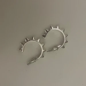 Silvriga örhängen med nitar - Coola silvriga örhängen i form av halvcirklar med spetsiga nitar runtom. Perfekta för att ge en edgy touch till din stil. Lätta att bära och passar till många olika outfits. Från gina tricot, aldrig använda