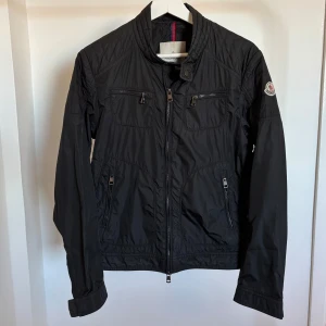 Svart jacka från Moncler - Snygg svart vårjacka från Moncler med dragkedja och broderad logga på ärmen. Storlek 1/s. Modellen heter Moncler donatien giubbotto. Iproncip oanvänd.
