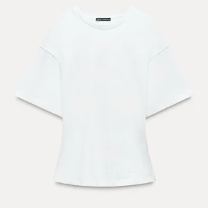 Vit t-shirt med dragkedja från Zara - Snygg vit t-shirt från Zara med en unik dragkedja längs ryggen. Den har en avslappnad passform och korta ärmar, perfekt för en stilren outfit 💕