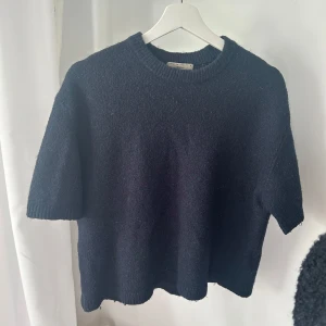 Mörkblå stickad  - Säljer en stilren mörkblå stickad tröja från Gina tricot . Tröjan har korta ärmar och en rund halsringning💕lite noppig 
