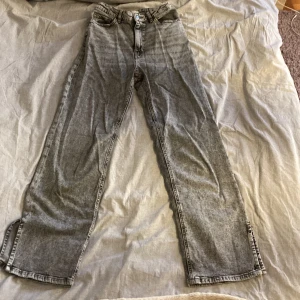 Grå jeans från Lindex - Snygga grå jeans från Lindex med en klassisk straight fit. De har en knapp och dragkedja framtill samt fem fickor. Perfekta för en avslappnad stil. Är i hyfsat bra skick säljer för att dom är för små kontakta mig för mer 🤍