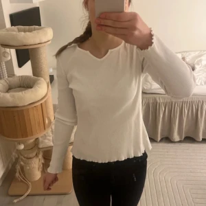 Vit ribbad tröja - Säljer en stilren vit ribbad tröja med långärmad design och v-ringad hals. Perfekt för en enkel och snygg look. Passar bra till både jeans och kjol.