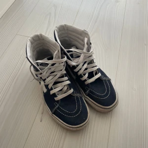 Blåa vans - Säljer nu mina blåa sneakers från Vans med vita snören och detaljer. Skorna har en hög modell med klassisk design och är perfekta för en avslappnad stil. Mycket sparsamt använda! 