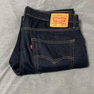 Levi's 502 jeans - Snygga Levi's 502 jeans i mörkblå denim. Klassisk design med fem fickor och guldfärgade sömmar. Perfekta för en avslappnad stil med en straight passform. Märkeslappen i läder baktill ger en autentisk touch.