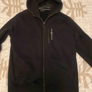 Svart hoodie från Sail Racing - Säljer en svart hoodie från Sail Racing med dragkedja och huva. Den har en diskret logga på bröstet och är tillverkad i ett mjukt material. Fläckar som går bort genom tvätt, innan varan fraktas tvättas den.